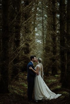 a bride and groom kissing in the woods