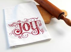 a wooden rolling pin sitting on top of a white napkin with the word joy printed on it