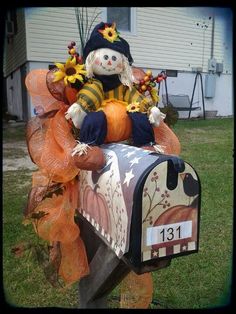 a mailbox decorated with a scarecrow and sunflowers