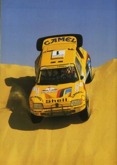 a yellow rally car driving through the sand dunes