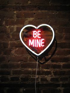 a neon sign that says be mine in the shape of a heart