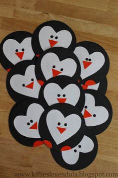 a bunch of penguins that are sitting on top of a wooden table with hearts painted on them