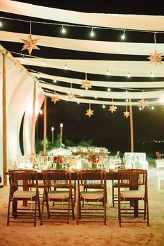 an outdoor dining area is lit up with string lights and star - shaped decorations on the ceiling