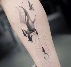 a woman's leg with an orca whale tattoo on it and some birds flying around