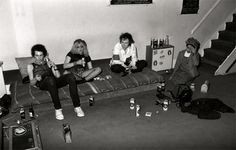 black and white photograph of four people sitting on a couch with beer cans scattered around them