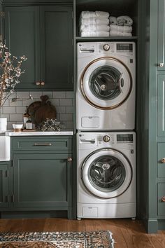 a washer and dryer in a kitchen with green cabinetry, white counter tops and wooden floors