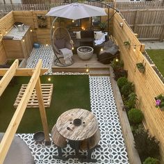 a small backyard with an umbrella over the table and chairs on the grass, next to a deck