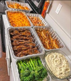 several trays of food sitting on top of a white counter next to an oven