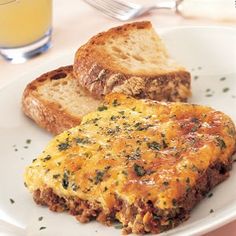 an omelet and bread on a plate with a glass of orange juice