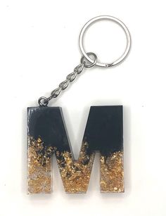 a black and gold letter keychain with the word m in it's center