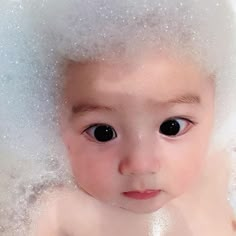 a close up of a baby with bubbles on it's head in the bathtub