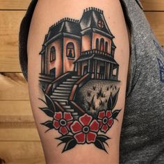 a man with a tattoo on his arm has a house and flowers in front of him