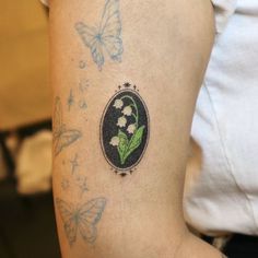 a close up of a person's arm with tattoos on it and butterflies flying around