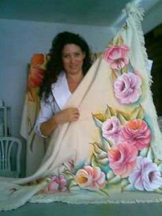 a woman is holding a blanket with flowers painted on it and posing for the camera