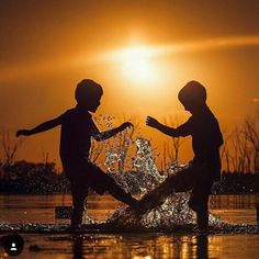 two children playing in water at sunset with the sun shining on their faces and arms