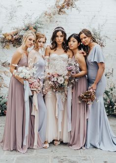 a group of women standing next to each other wearing dresses and holding bouquets in their hands