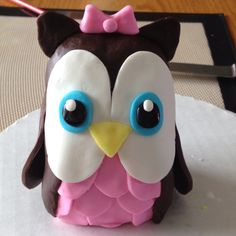 a cake shaped like an owl with blue eyes and a pink bow on its head