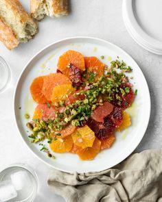 a white plate topped with sliced oranges and pistachio on top of a table