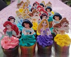 there are cupcakes with princesses on them sitting on a table in front of other cupcakes