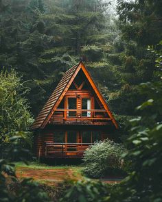 a wooden cabin nestled in the woods surrounded by tall pine trees and lush greenery