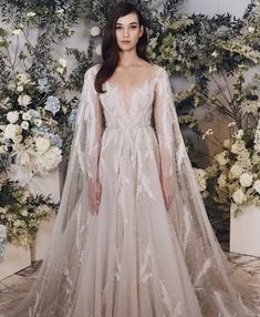 a woman standing in front of flowers wearing a wedding dress