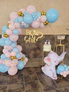 an elephant balloon arch with blue, pink and gold balloons for a baby's first birthday