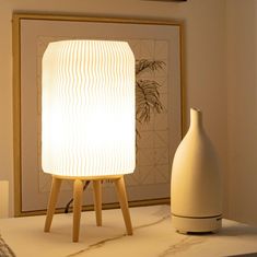 a white lamp sitting on top of a table next to a vase and framed photograph