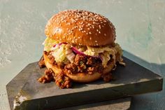 a sloppy joe sandwich with lettuce and coleslaw on a slate board