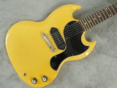 a yellow guitar laying on top of a gray blanket