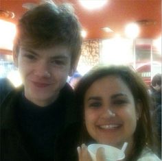 a young man and woman posing for the camera with coffee cups in their hands at a restaurant