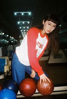 a woman leaning over some bowling balls