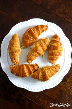 croissants on a white plate sitting on a wooden table