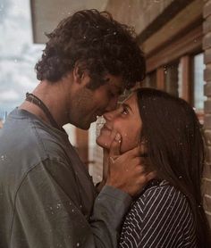 a man and woman standing next to each other near a brick wall with the sky in the background