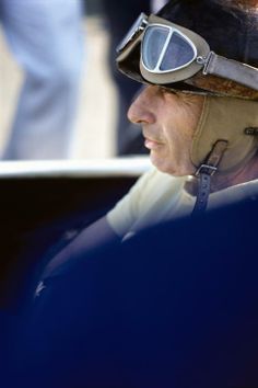 a man wearing a helmet and goggles sitting in a car with other people behind him