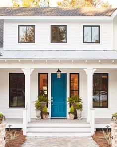 a white house with blue front door and two planters