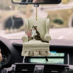 a cat sitting in a chair hanging from a car dashboard