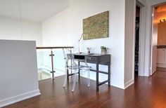 a desk and chair in the corner of a room with hardwood flooring on one side