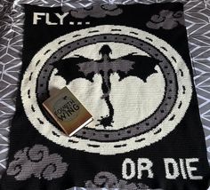 a book laying on top of a bed next to a black and white blanket with the words fly or die