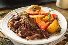 a white plate topped with roast, potatoes and carrots