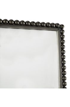 a silver framed mirror with beading around the edges