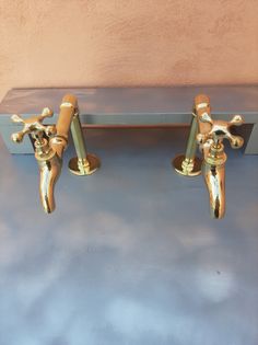 two brass faucets sitting on top of a blue table