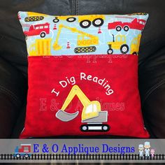 a red pillow with construction vehicles on it and the words dig reading e & o applique designs