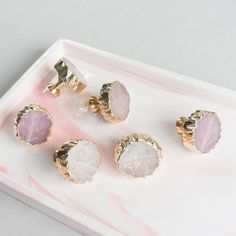 three pieces of jewelry sitting on top of a pink and white marble tray with gold accents