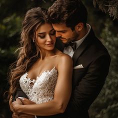 a bride and groom embracing each other in front of trees