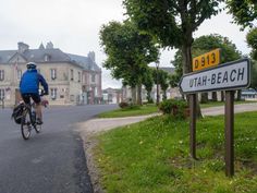 a bicyclist rides past a sign that reads utah beach