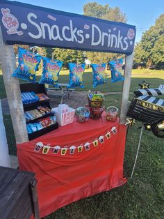 snacks and drinks are on display at an outdoor event in the grass, under a sign that reads snack's - drinks