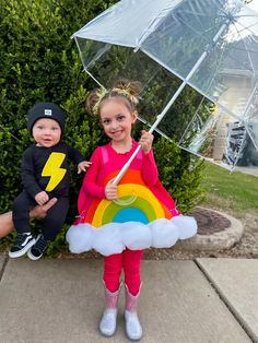 two children dressed up in costumes and holding umbrellas