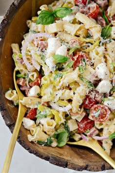 a wooden bowl filled with pasta salad on top of a table