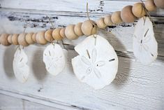 sand dollar ornaments hanging from a string on a white wooden wall with beads and wood bead