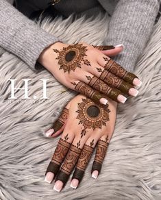 two hands with henna tattoos on them, one is brown and the other is white